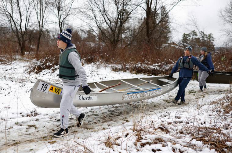 Clayde and Shawn Thompson carry their canoe through the snow to the starting line, with Leslie Voyer following behind.