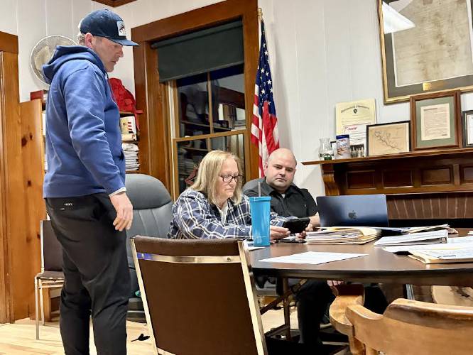 Jon Schaefer shows Charlemont Selectboard members Kim Blakeslee and Valentine Reid photos of a pump track during Monday’s meeting.