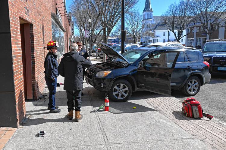 Greenfield Fire Department members talk with the driver of a car that jumped the curb on Main Street taking out a parking meter and damaging the Franklin County Community Justice Support Center in Greenfield on Monday.