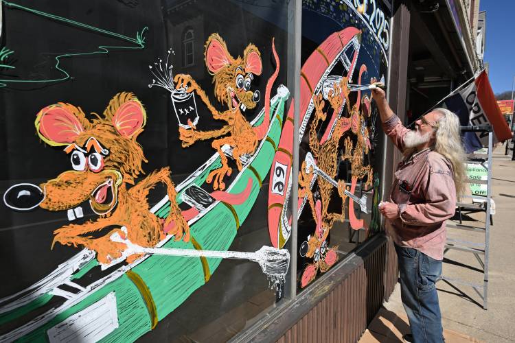 Leominster resident Steve Leger creates a mural on the window of the Mass Discount Center on Main Street in Athol on Wednesday to promote the 60th annual River Rat Race coming up on Saturday.