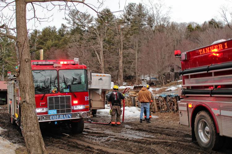 Firefighters pack up gear after extinguishing a fire at Hager’s Farm on Merrifield Lane in Colrain on Wednesday.