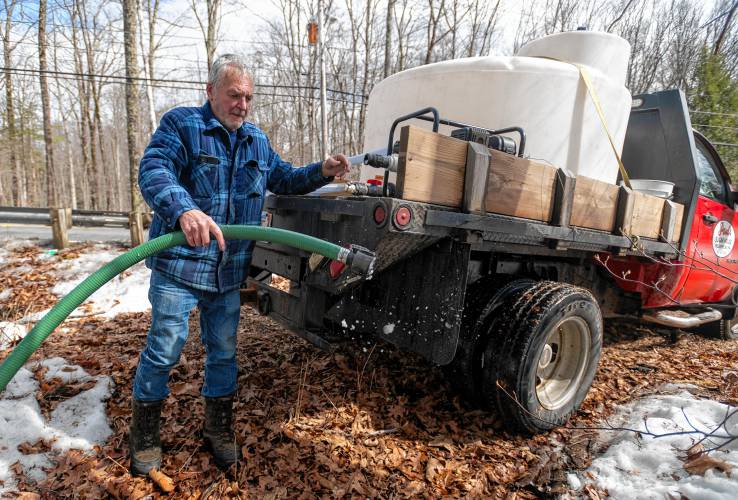 Paul’s Sugar House owner Paul Zononi clears debris out of a pipe before collecting sap from a tank Thursday, outside of Williamsburg.