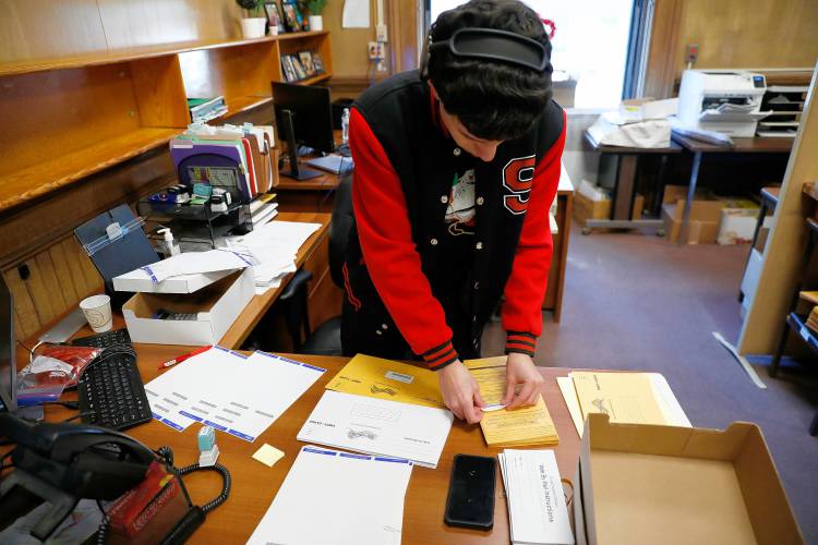 Temporary worker Jimmy Serrano preps mail-in ballots Friday at the Holyoke City Clerk’s Office.