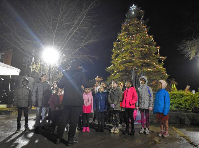 The Twice As Smart choir sings in front of the Christmas tree at Veterans Mall in Greenfield on Friday night.