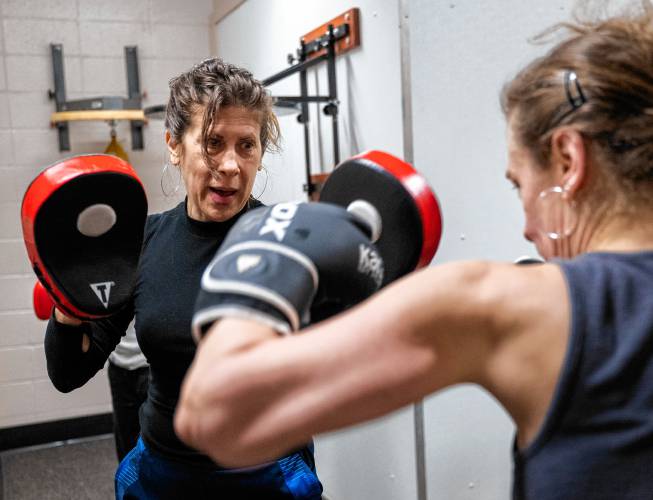 Instructor Vanessa Chakour, left, trains with Irene McGarrity during her women’s boxing class at Franklin County’s YMCA.
