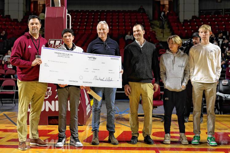 Bement School eighth grader Sebastian Garro (second from left) receives a check from UMass athletic director Ryan Bamford during halftime of the school’s men’s basketball game against St. Joseph’s on Tuesday night at the Mullins Center in Amherst.