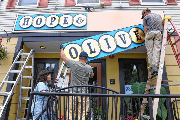 After 17 years at the corner of Hope and Olive streets in Greenfield, the Hope & Olive restaurant recently had a new sign installed thanks to a Storefront Improvement Grant from the city and the talents of Jess Marsh Wissemann, left, of Hired Hand Signs out of Turners Falls. She was assisted by her husband, David Wissemann, and Liam Sullivan.