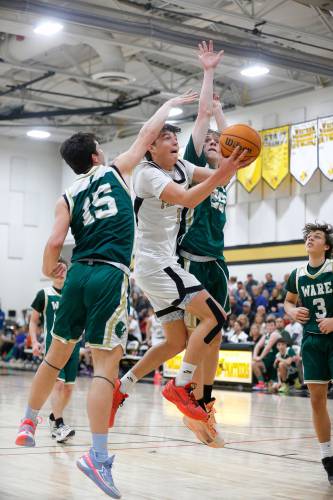 Pioneer’s Kurt Redeker (3) drives to the hoop between Ware defenders Jack Gaudreau (15) and Justin Grout (25) in the second quarter of the MIAA Division 5 quarterfinal Friday night in Northfield.