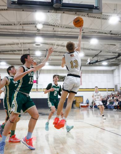 Pioneer’s Judah Glenn (13) puts up a reverse layup past Ware defender Jack Gaudreau (15) in the third quarter of the MIAA Division 5 quarterfinal Friday night in Northfield.