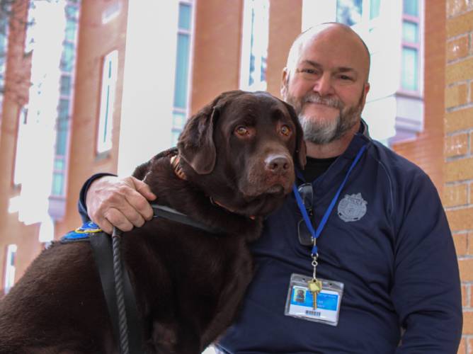 Two hundred and sixty-five students and staff members at Turners Falls High School and Great Falls Middle School have signed a petition advocating to keep School Resource Officer Dan Miner, whose position is set to be eliminated as part of fiscal year 2026 budget cuts. Miner is pictured here with K-9 Mack, the school’s comfort dog. Two hundred and sixty-five students and staff members at Turners Falls High School and Great Falls Middle School have signed a petition advocating to keep School Resource Officer Dan Miner, whose position is set to be eliminated as part of fiscal year 2026 budget cuts. Miner is pictured here with K-9 Mack, the school’s comfort dog.