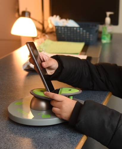 A Greenfield Middle School student locks a cellphone in a Yondr pouch upon arriving at school in 2023.